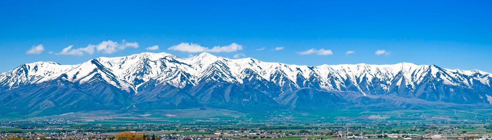 Snow-capped Wellsville Mountains rising over the green farmland of Cache Valley, Utah.